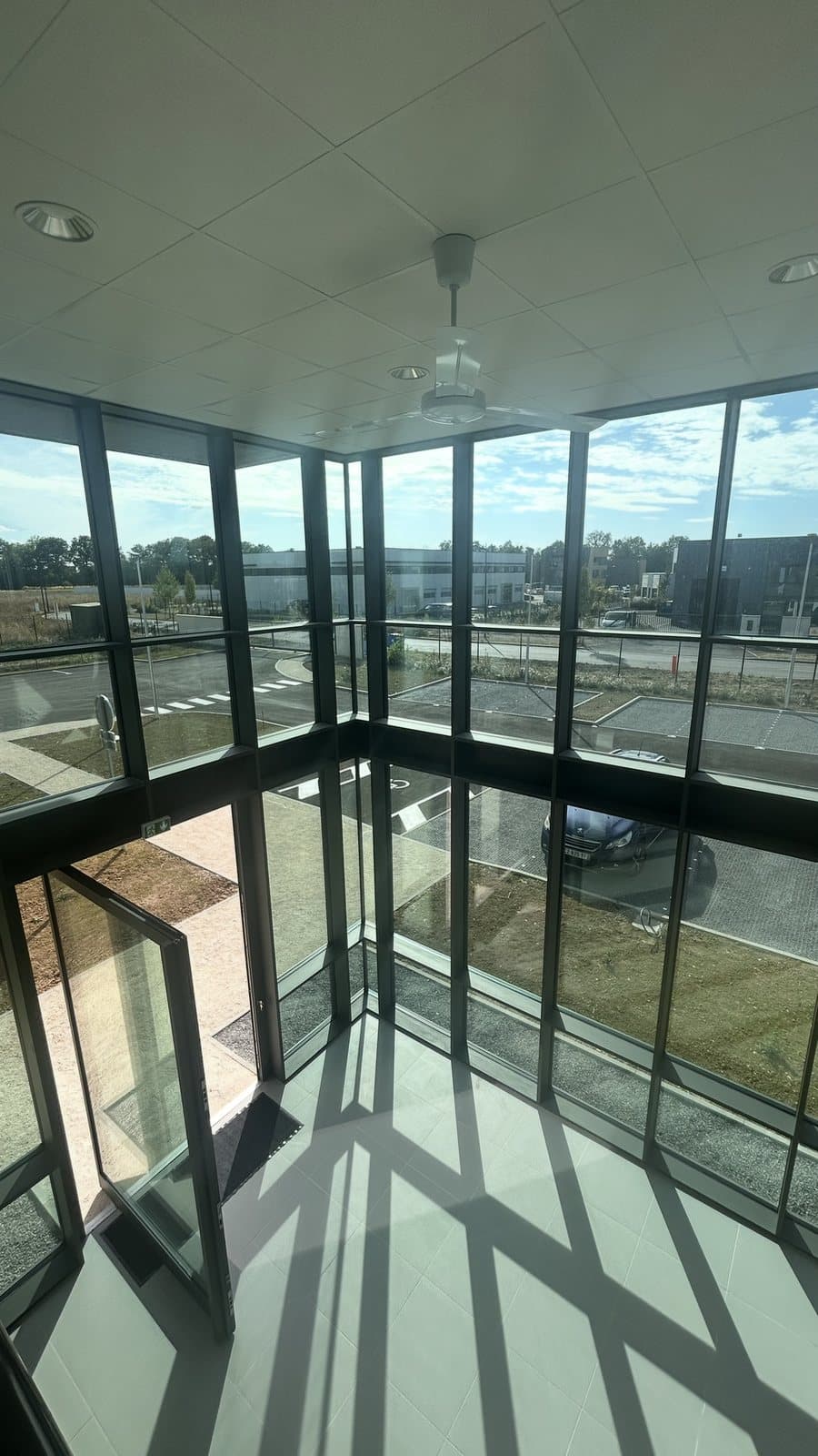 Angle vitré du hall vu depuis la mezzanine, mur rideau minimaliste