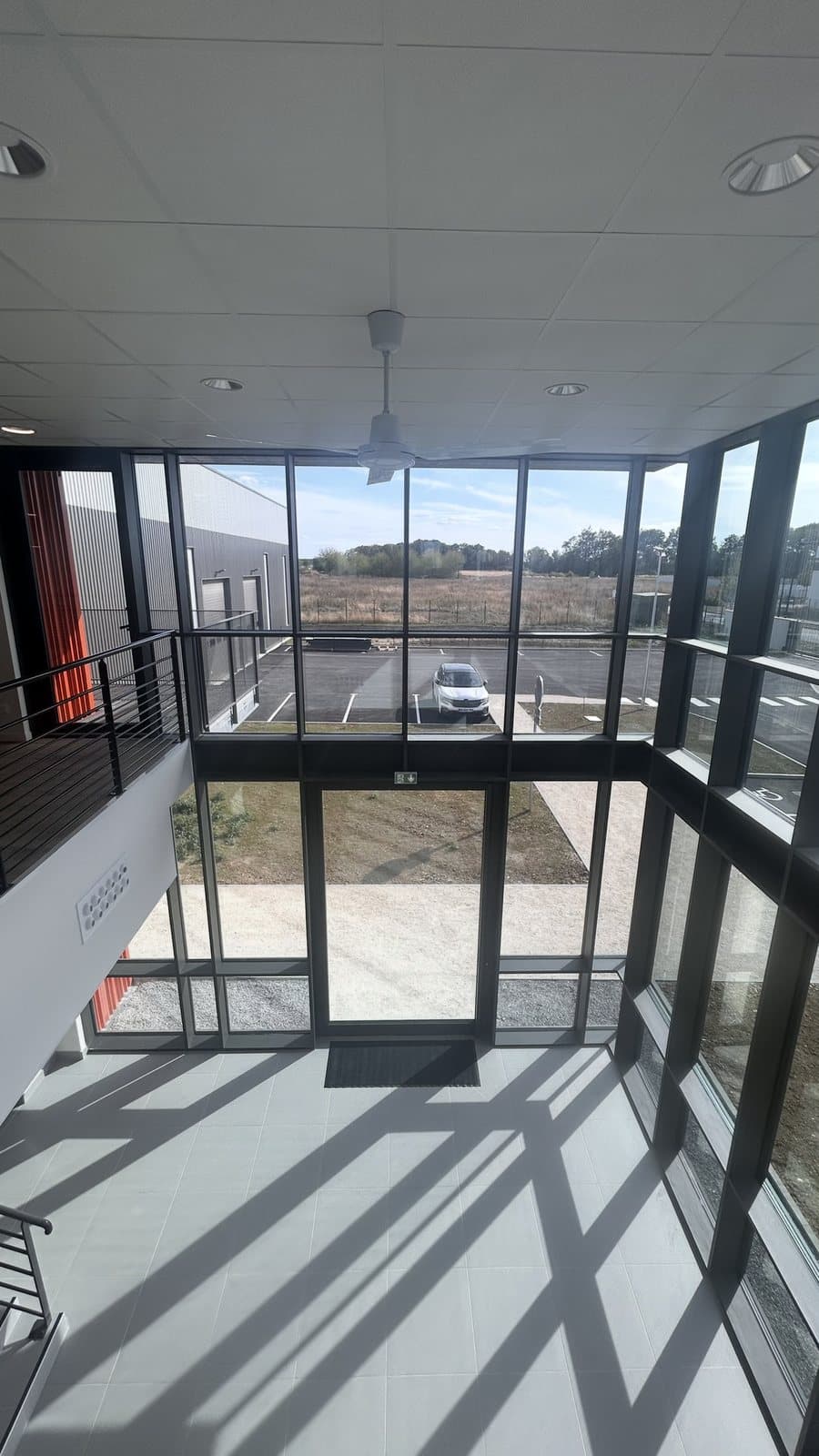 Vue du hall depuis la mezzanine vers le parking, mur rideau SlimWall 35