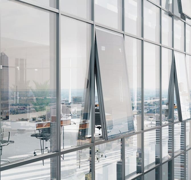 Mur-rideau Reynaers CW 50 — façade vitrée d'immeuble tertiaire avec ouvrants oscillants, bureaux et vue ville