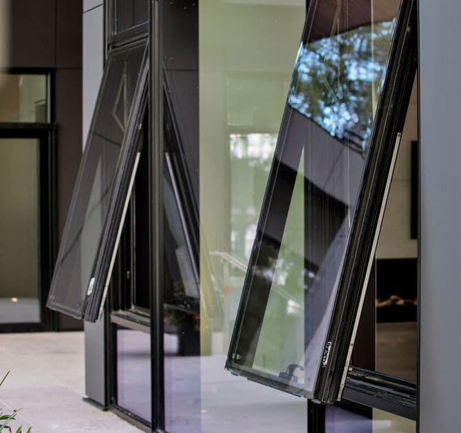 Mur-rideau Reynaers CW 50 à cadres noirs avec ouvrants oscillants vers l'extérieur autour d'un patio vitré